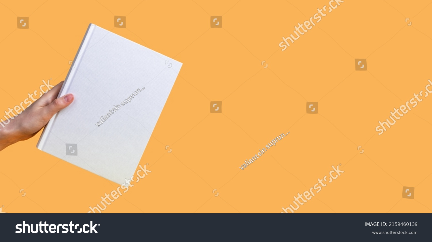 Banner with hand holding book mockup on orange background. Education, reading hobby, wisdom, intellectual development concept. Copy space. High quality photo #2159460139