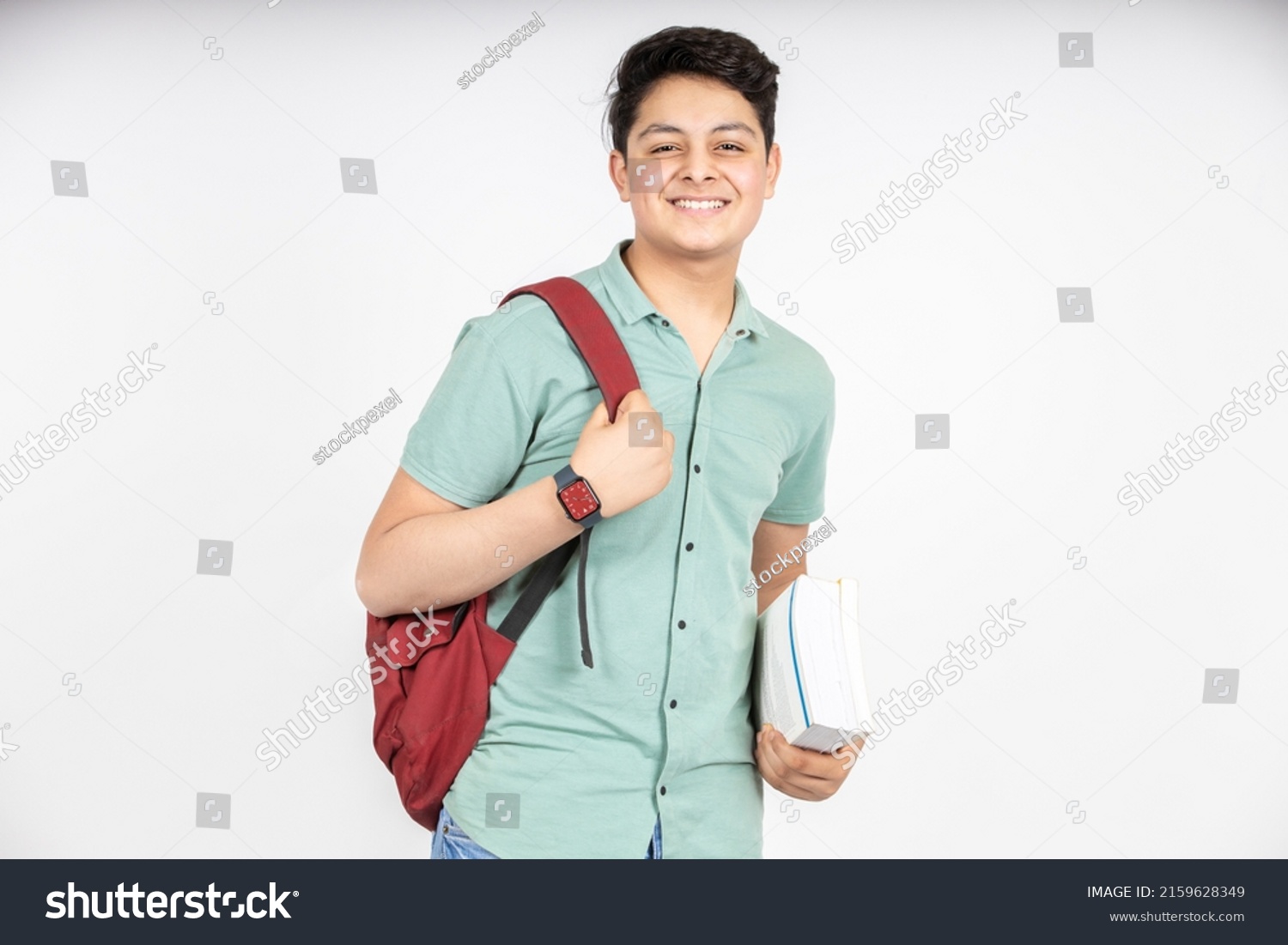 Portrait of happy indian teenager college or school boy with backpack holding books, isolated on white background. Smiling young asian male kid looking at camera. #2159628349