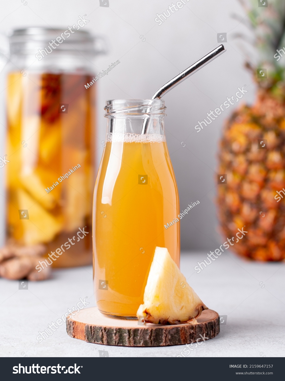 Fermented pineapple beverage tepache in reusable glass bottles with metal drinking straws and glass pitcher on light gray background #2159647157