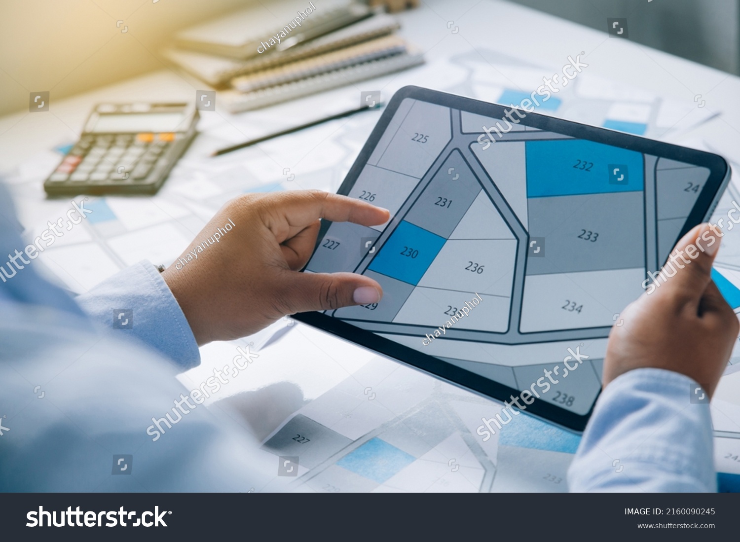 Man holding a tablet looking at lots of lands. Land plot management - real estate concept with vacant land for building construction and housing subdivision for sale, rent, buy, or investment #2160090245