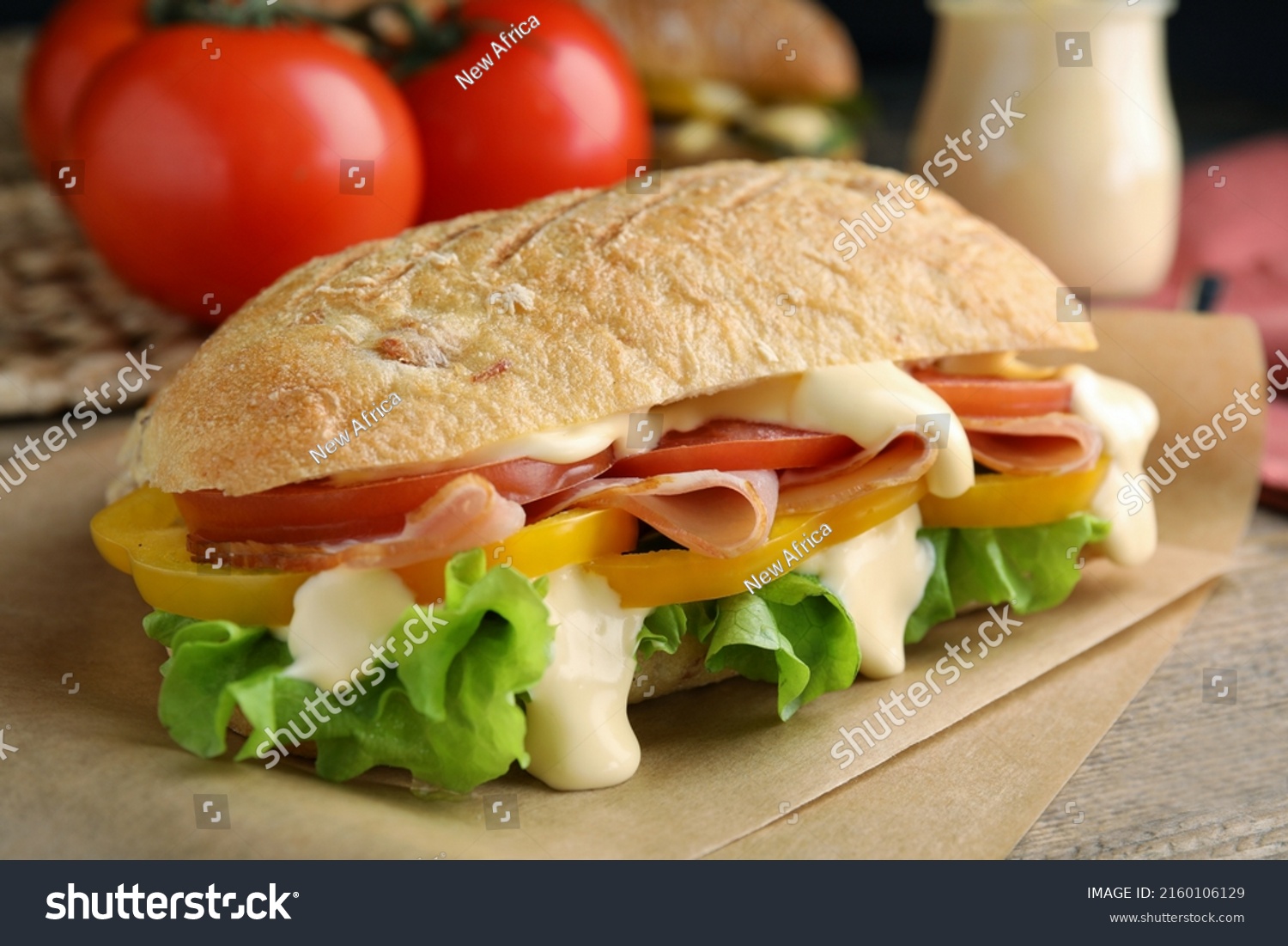 Delicious sandwich with vegetables, ham and mayonnaise served on wooden table, closeup #2160106129