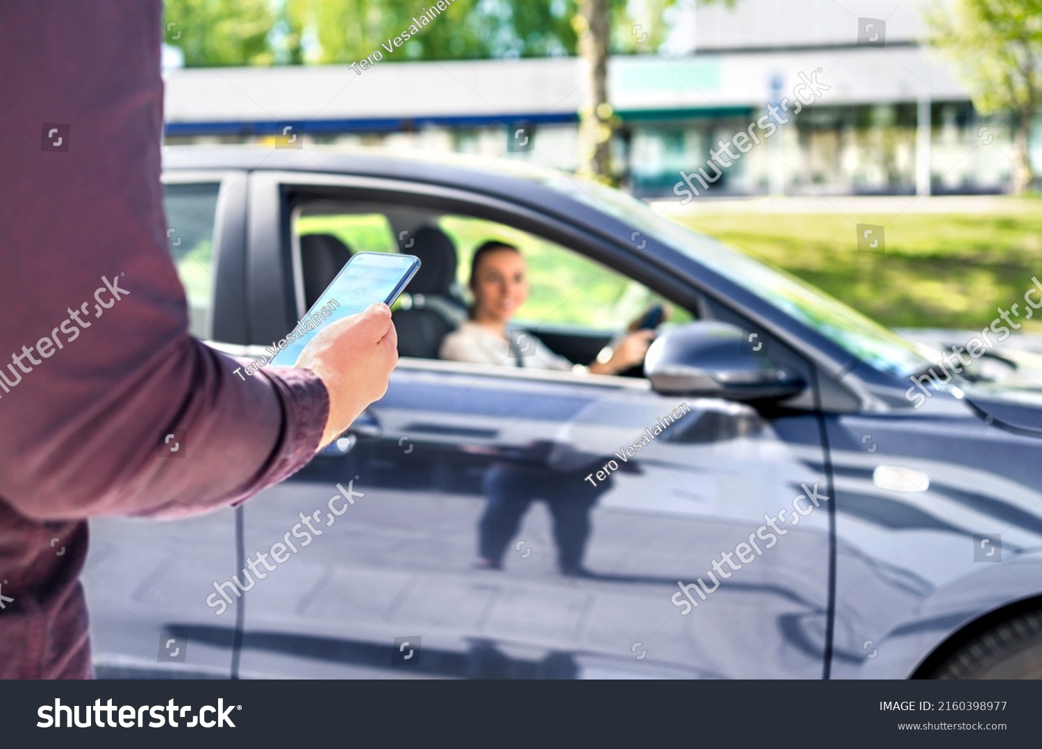 Taxi phone app for cab or car ride share service. Customer waiting driver to pick up on city street. Man holding smartphone. Mobile and online booking for rideshare transportation with cellphone. #2160398977
