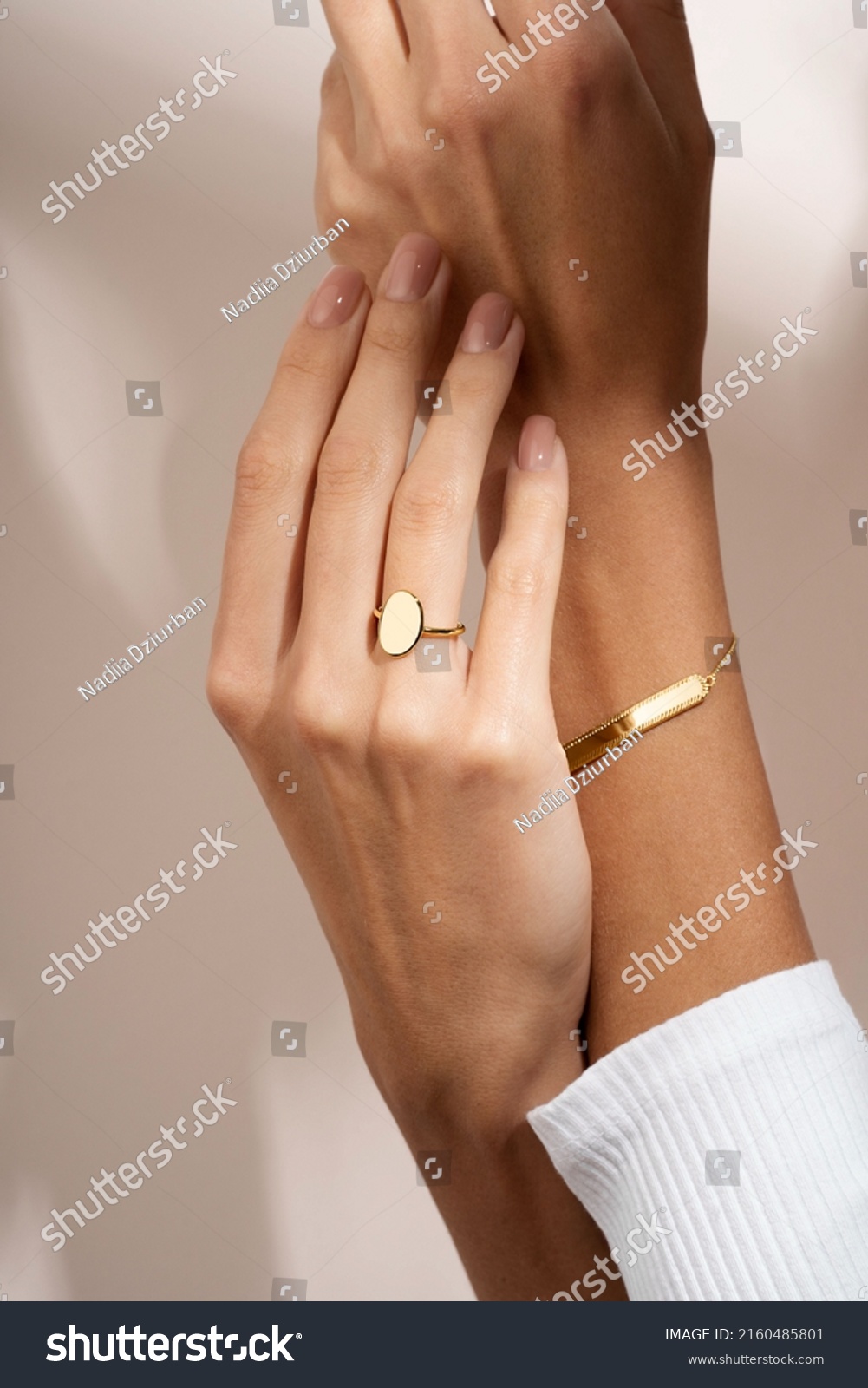 Woman Jewelery concept. Woman’s hands close up wearing rings and bracelet modern accessories elegant life style. Beige background  #2160485801
