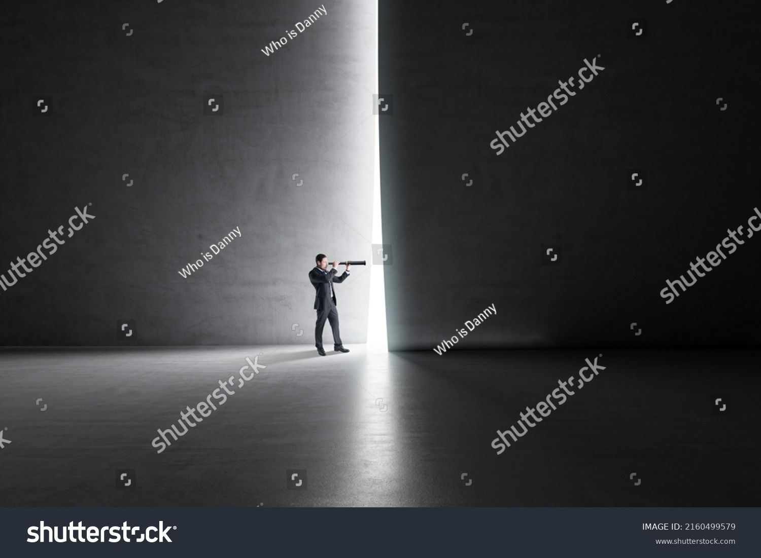 Looking in the future and busines development concept with businessman back view using spyglass looking through a light hole in a dark wall in empty spacious hall #2160499579