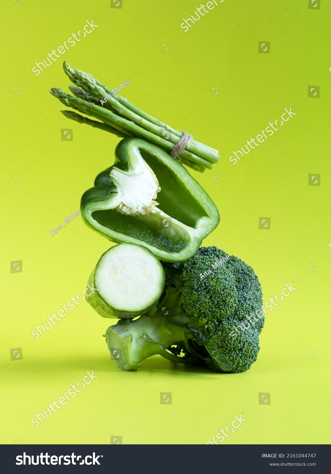 Fresh green vegetables balance on the table. Equilibrium floating food balance of broccoli, bell pepper, zucchini and asparagus on a green background #2161044747