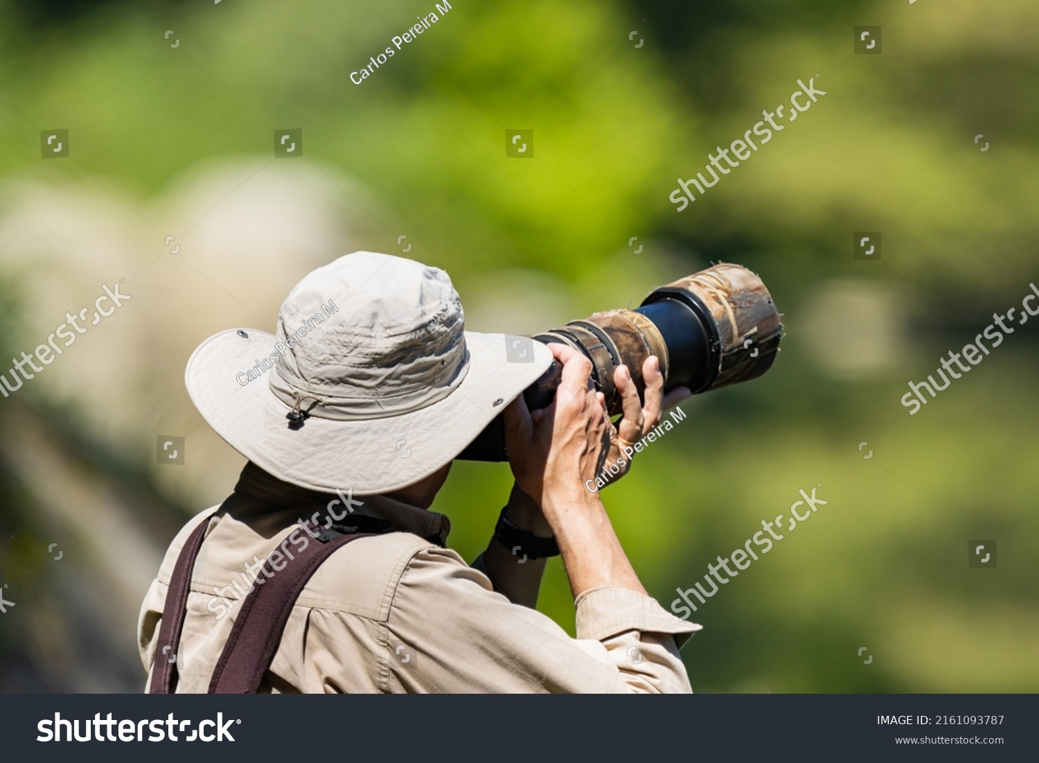 Wildlife photographer using a telephoto lens with camouflage coating. #2161093787