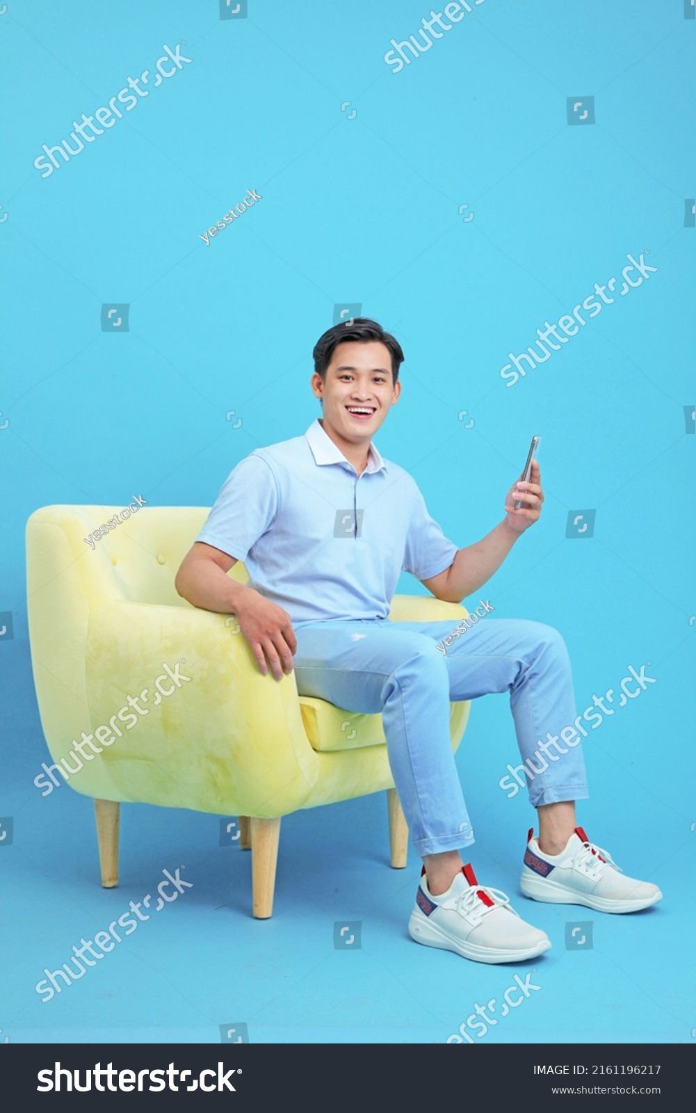 Asian handsome and cheerful young man using smart phone, sit on sofa, isolated on background #2161196217