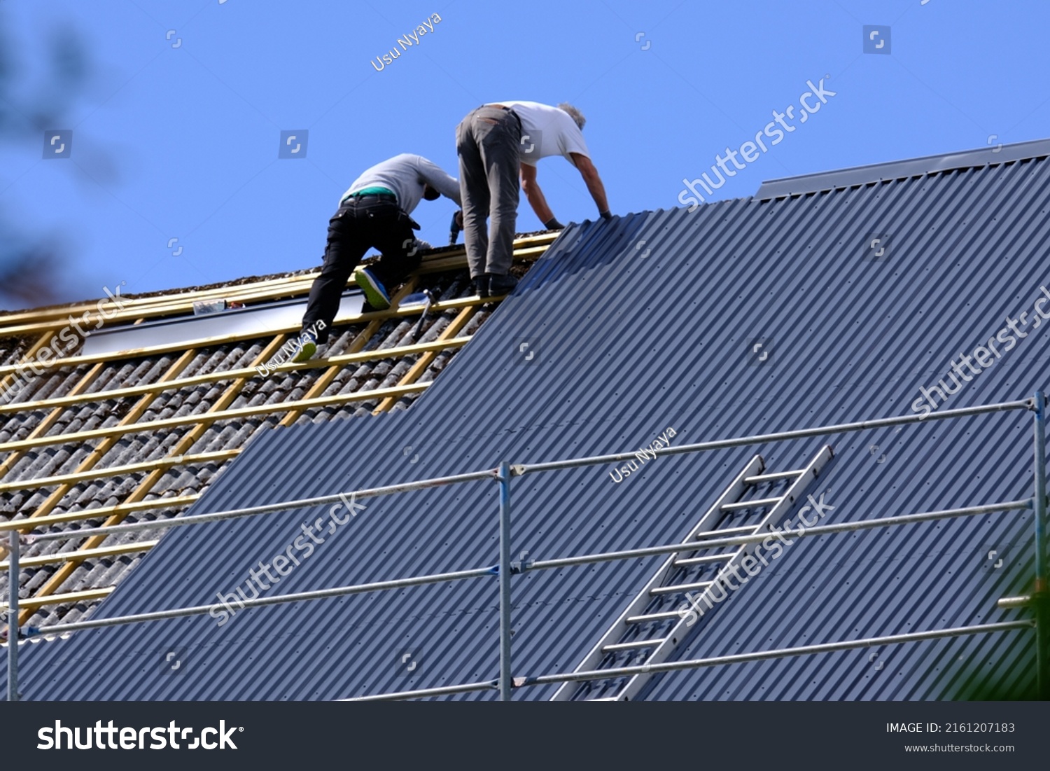 Two carpenters are replacing roof tiles in Norway. #2161207183
