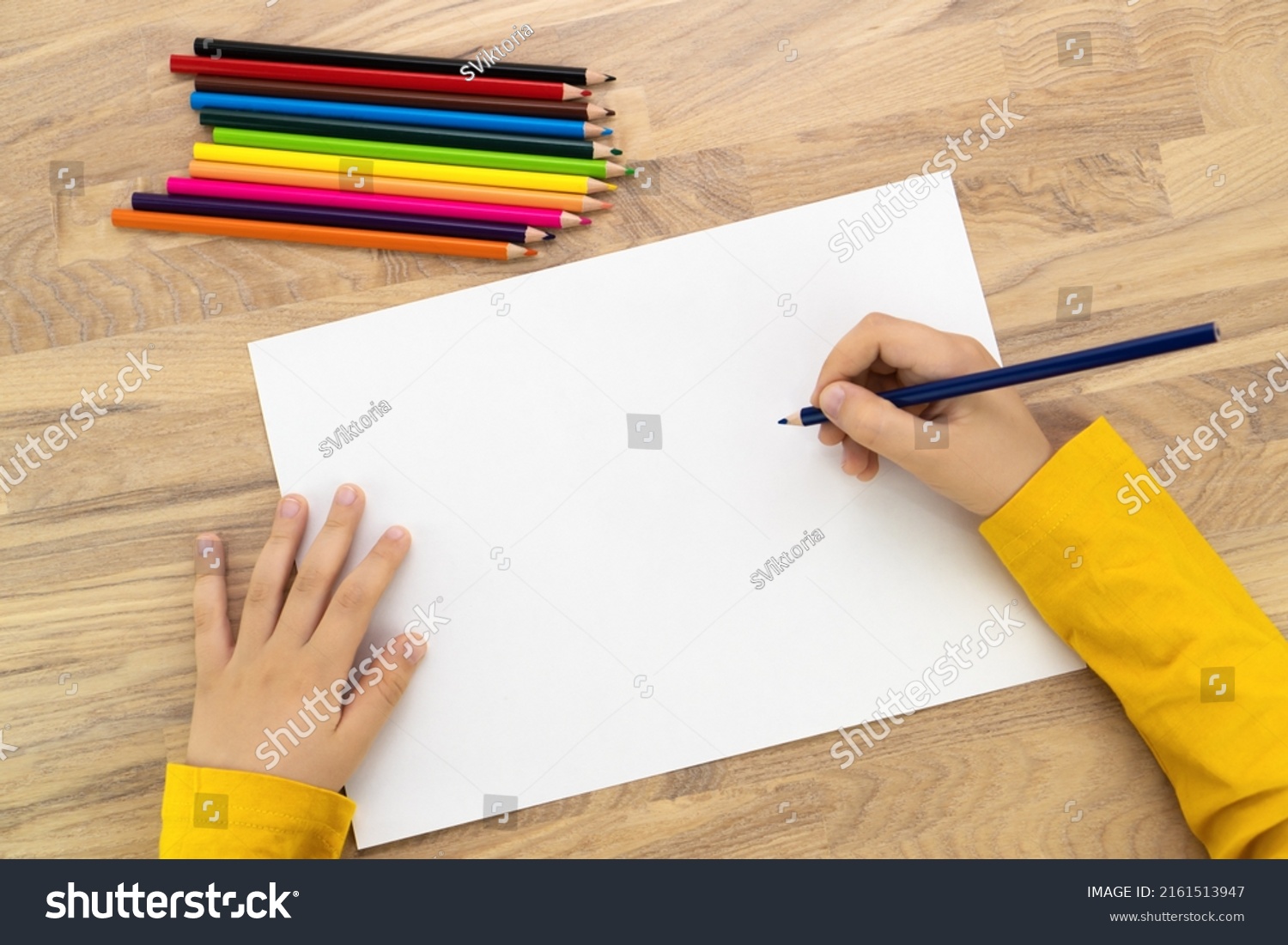 Child hands drawing with pencil on white paper, top view. Kids painting mock up. #2161513947