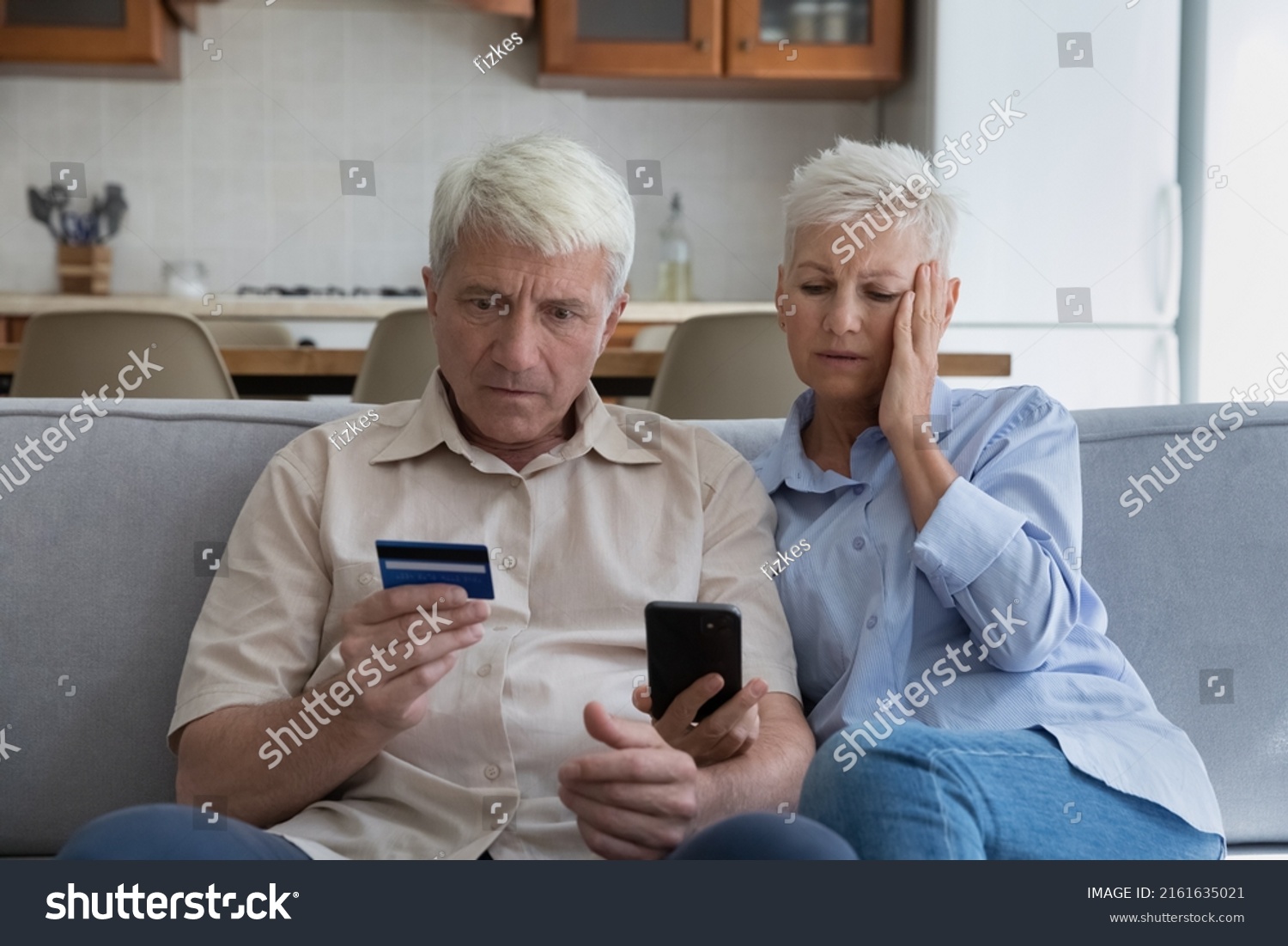 Shocked aged couple become victims of online fraud using credit card phone to pay for goods order service online on suspicious website. Frustrated older spouses overspending money at internet shopping #2161635021