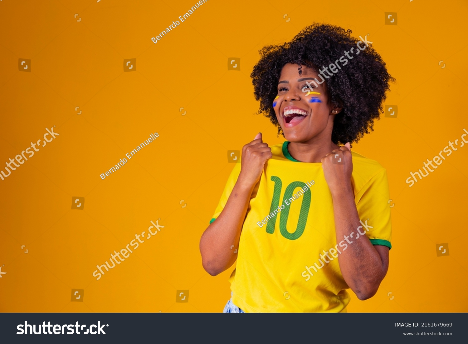 Brazilian fan. wearing Brazilian flag in a portrait, Brazilian fan celebrating football or soccer game on yellow background. Colors of Brazil.World Cup #2161679669
