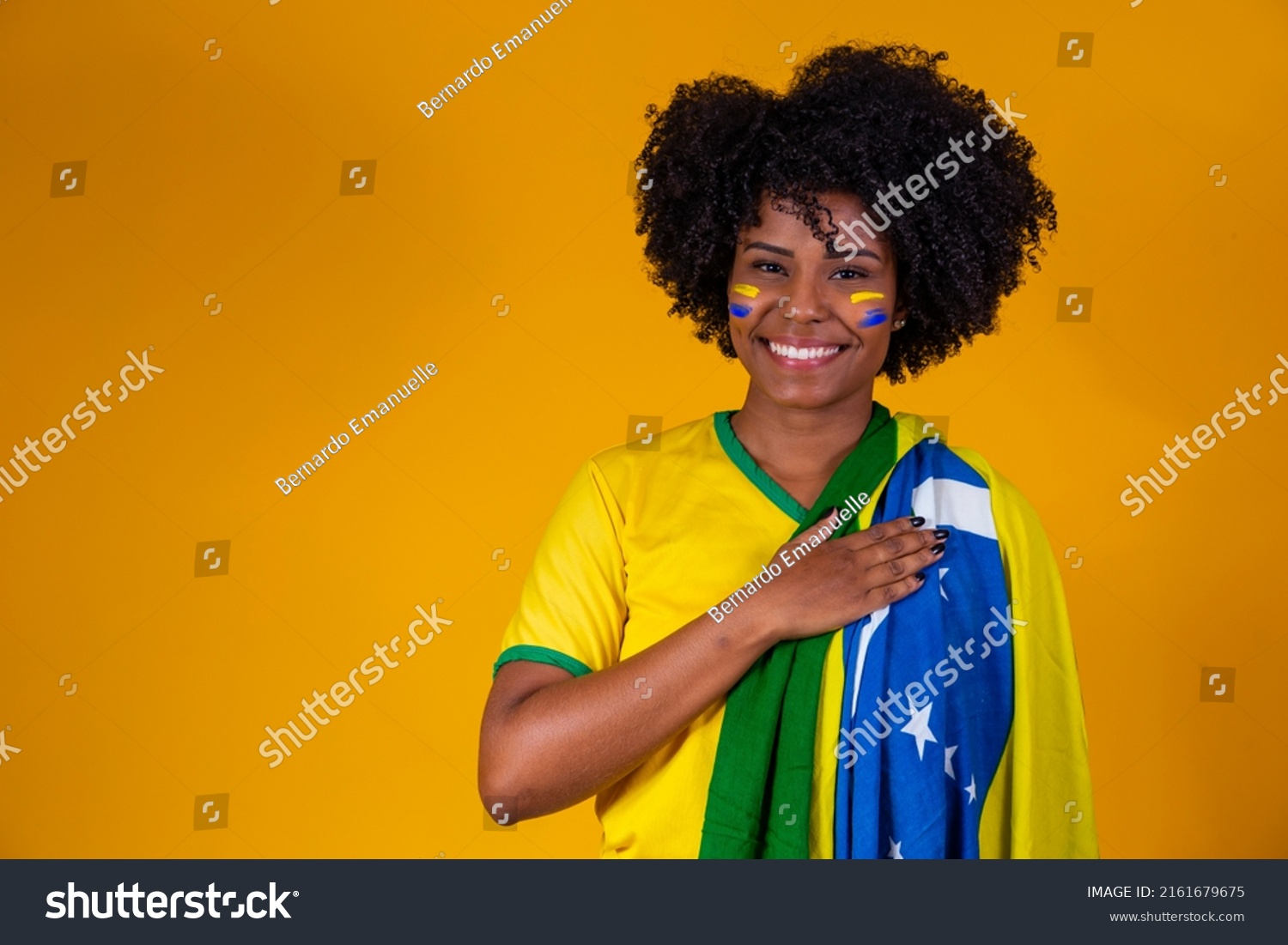 Brazilian fan. wearing Brazilian flag in a portrait, Brazilian fan celebrating football or soccer game on yellow background. Colors of Brazil.World Cup #2161679675