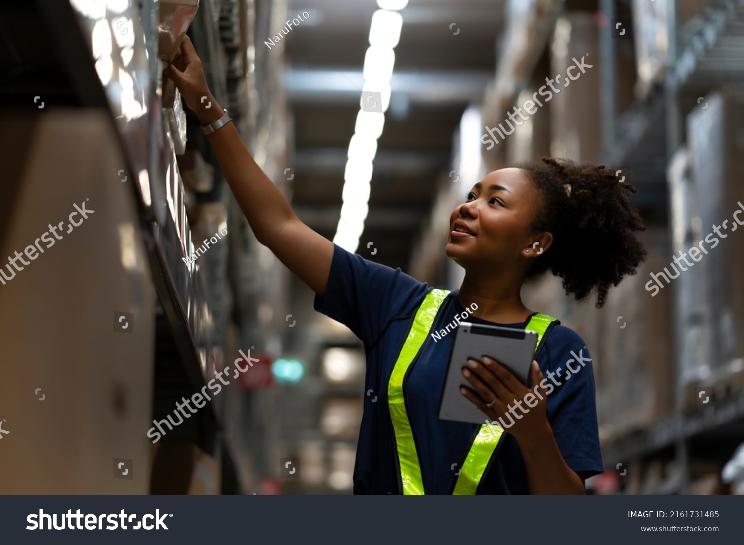 African American worker checking the stock on shelf in warehouse comparing the balancing number in system after delivery shipment. Using tablet to update online stock available for selling on website #2161731485