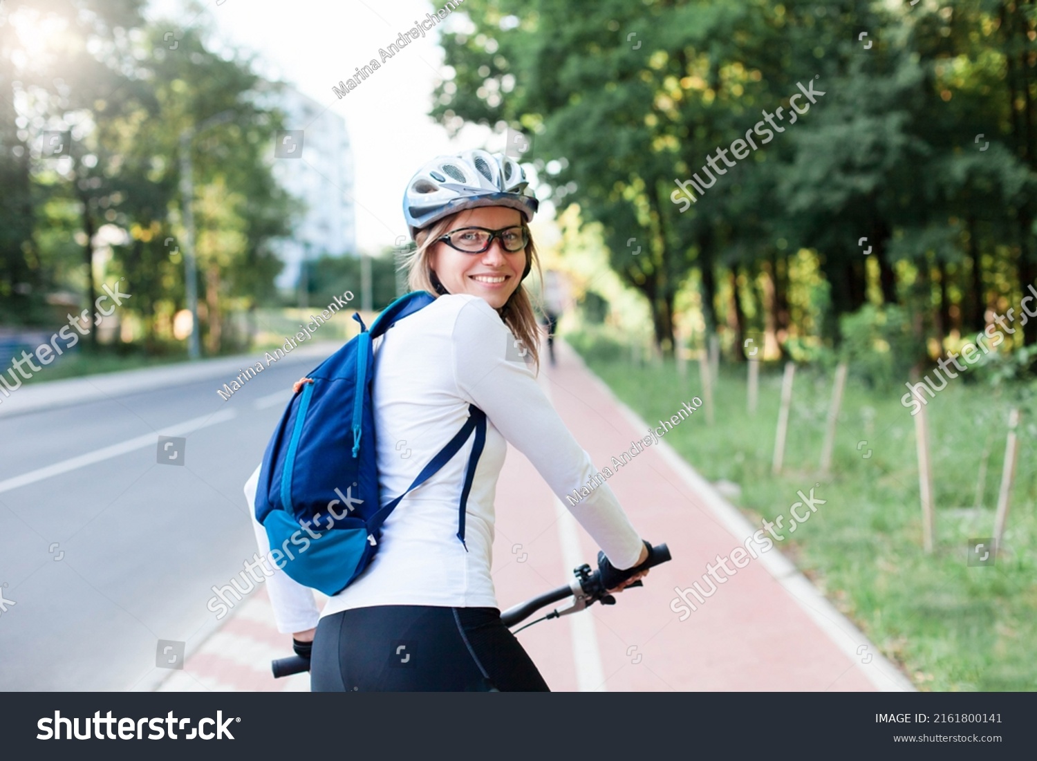 Happy woman riding bike on city street. Road with bicycle path. Cyclists #2161800141