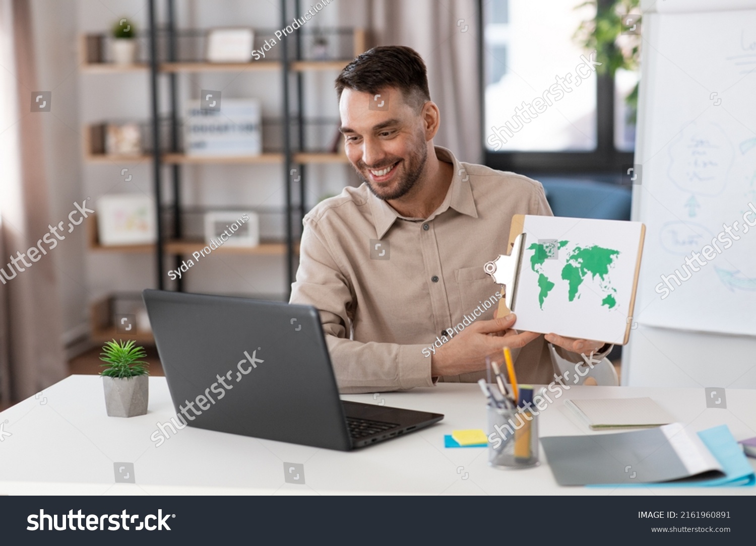 distance education, school and remote job concept - happy smiling male geography teacher with world map and laptop computer having online geography class at home office #2161960891