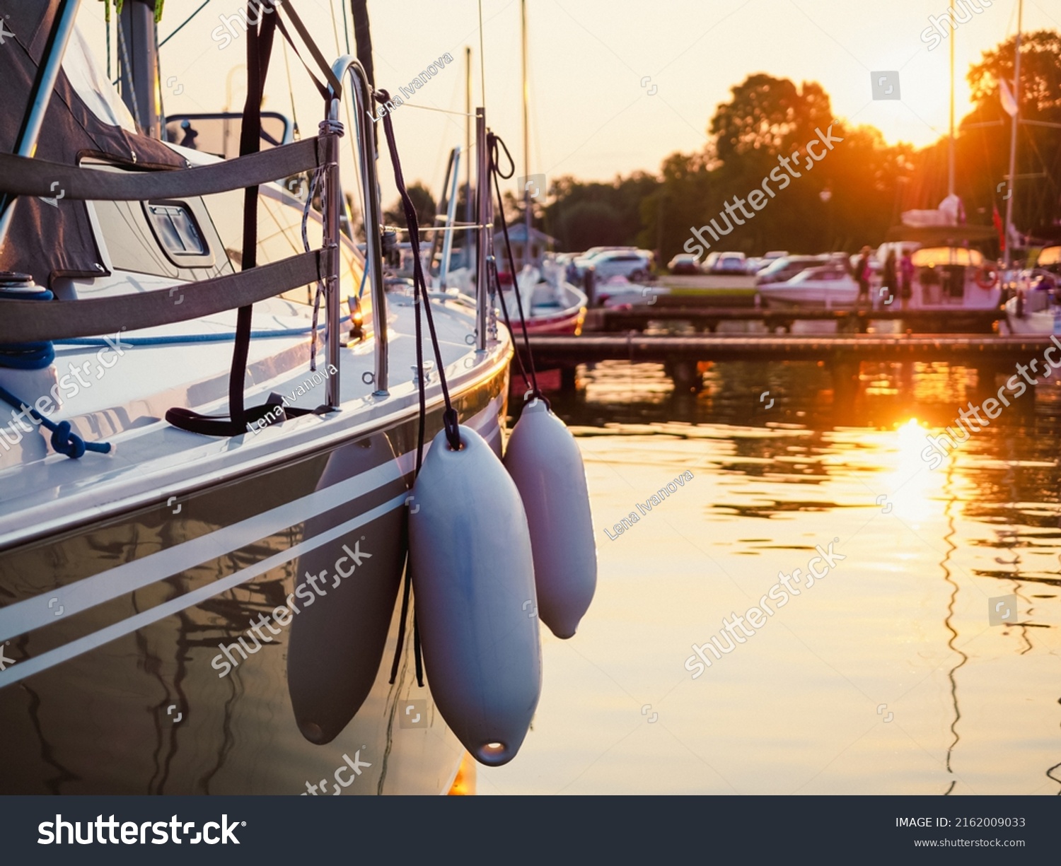 sunset view on sailing yacht moored on jetty in the port, close up view on sailboat hull, bow and fenders #2162009033