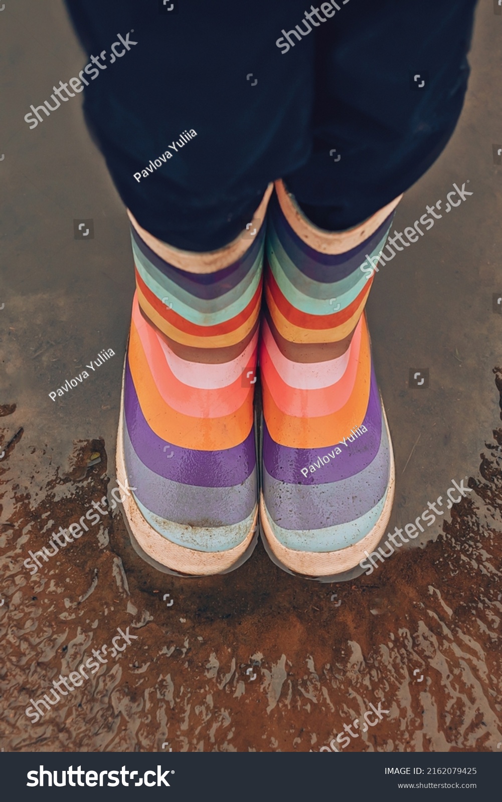 Rubber multicolored boots close-up in a puddle on the street #2162079425