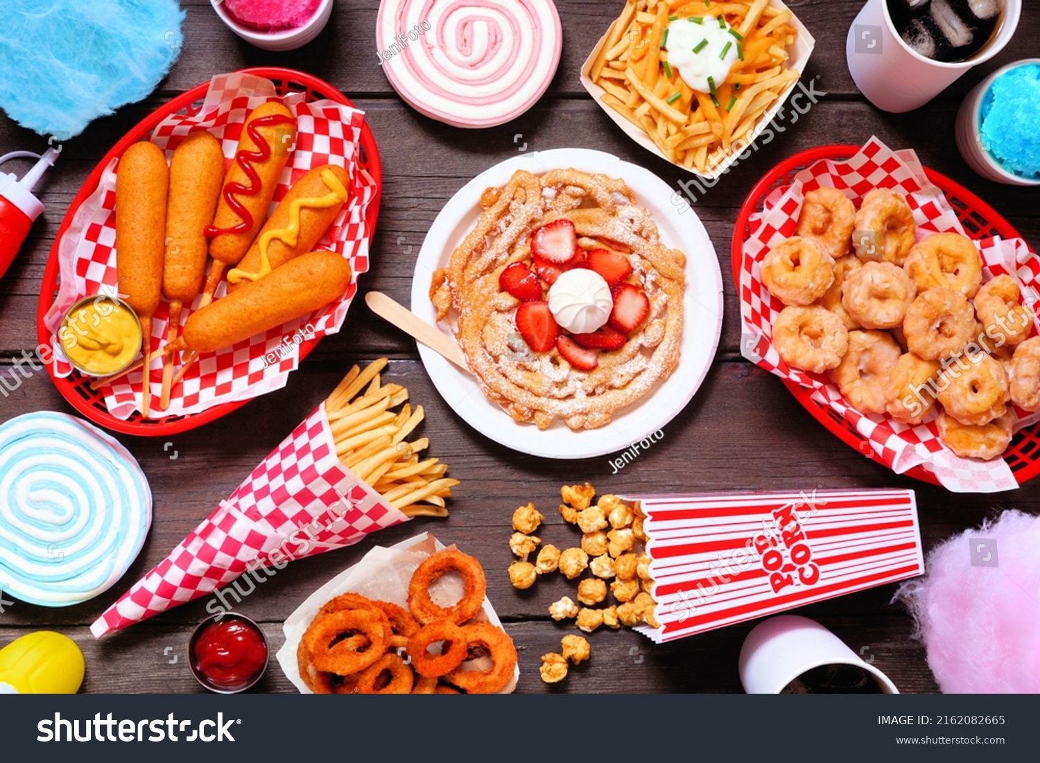 Carnival theme food double border over a dark wood background. Above view with copy space. Summer fair concept. Corn dogs, funnel cake, cotton candy and snacks. #2162082665