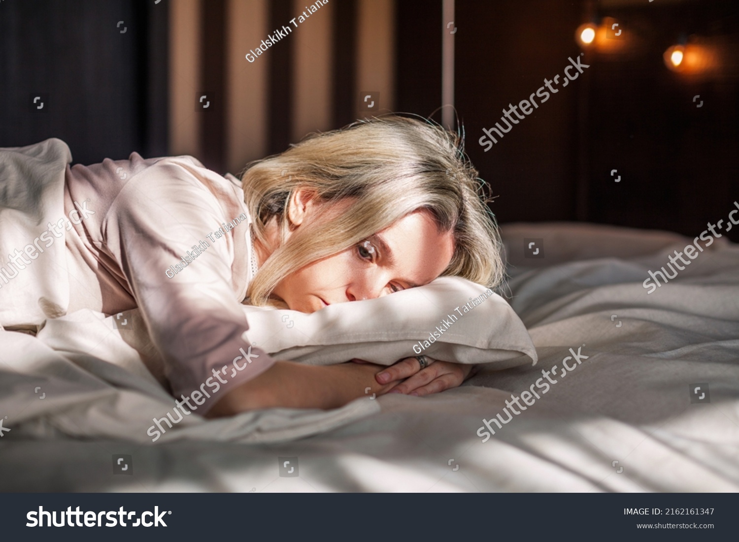 Tired middle aged woman lying in bed can't sleep late at morning with insomnia. Adult lady sick or sad depressed sleeping at home.
 #2162161347