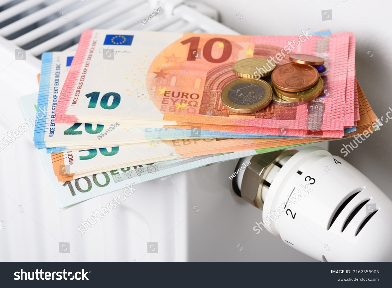 Euro money banknotes on heating radiator battery with thermostat temperature regulator. Concept of expensive heating costs and rising energy bill prices for winter cold season. #2162356903