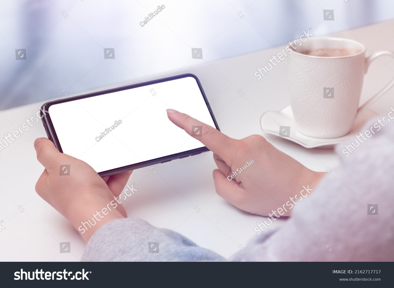 mockup cellphone horizontal position. Cropped shot view of female hands holding cellphone with blank screen for text in cafe. woman typing text on phone in cafe at white table #2162717717