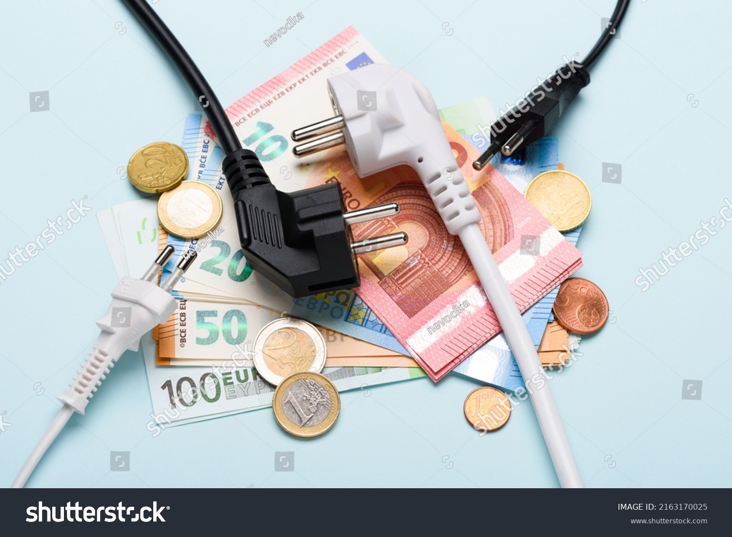 Electric power plugs on Euro banknotes on blue background. Concept of expensive electricity costs and rise in energy bill prices. #2163170025