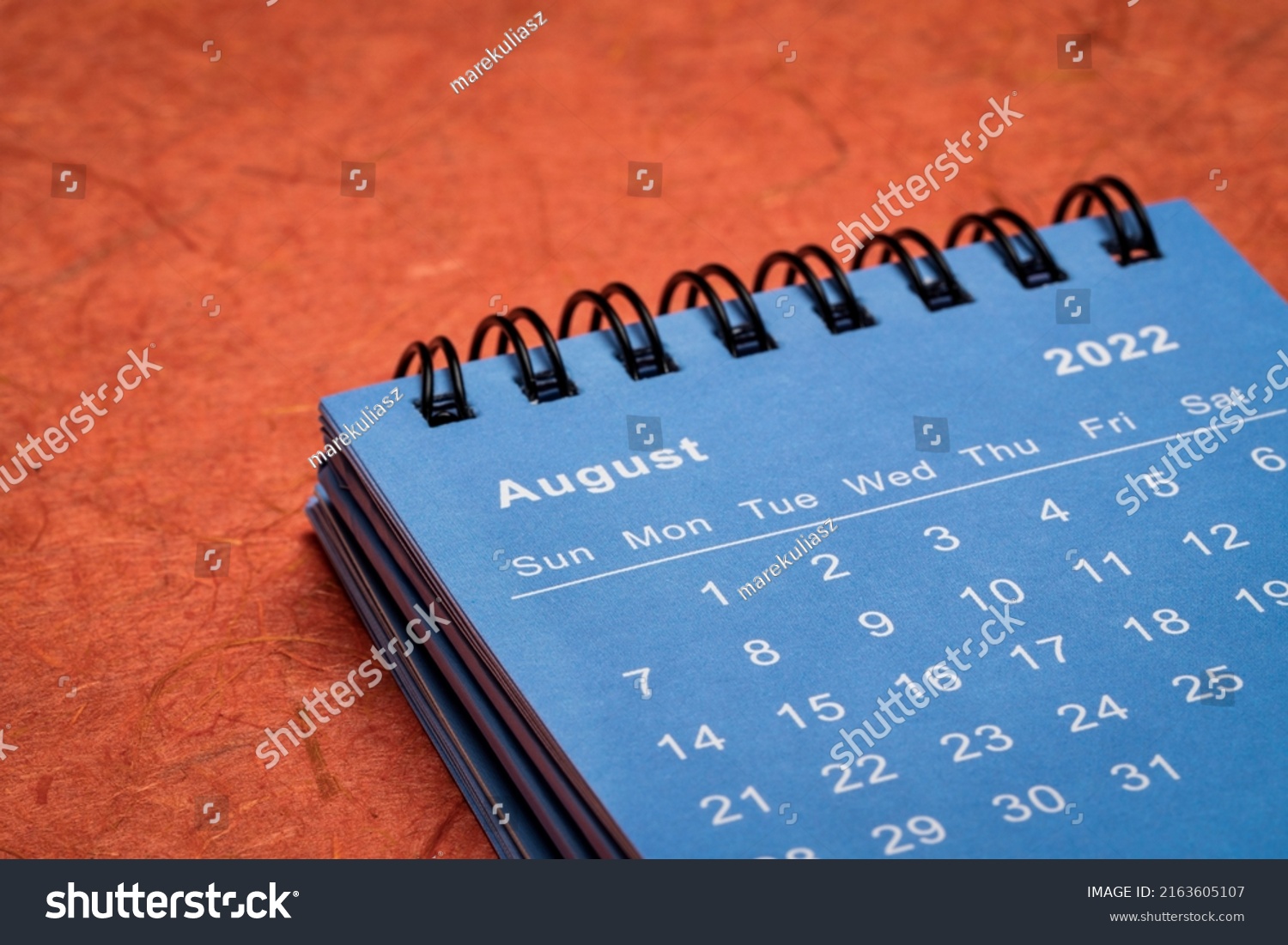 August 2022 - spiral desktop calendar against red mulberry paper, time and business concept #2163605107