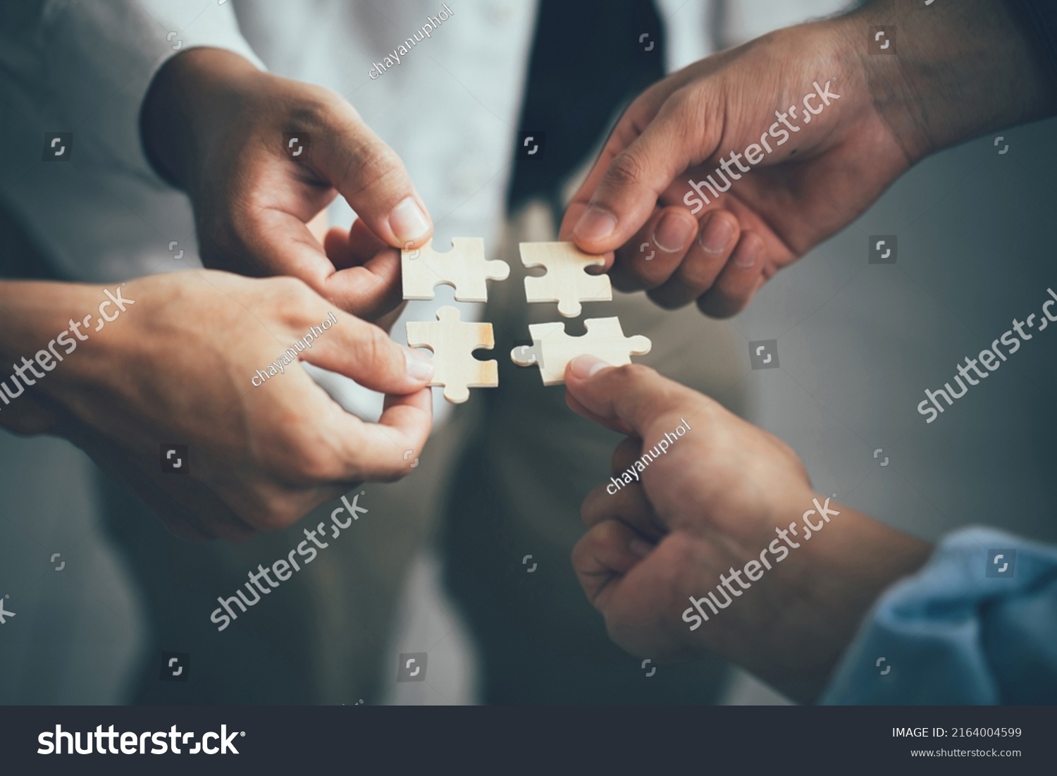 Concept of teamwork and partnership. Hands join puzzle pieces in the office. business people putting the jigsaws team together.Charity, volunteer. Unity, team business. #2164004599