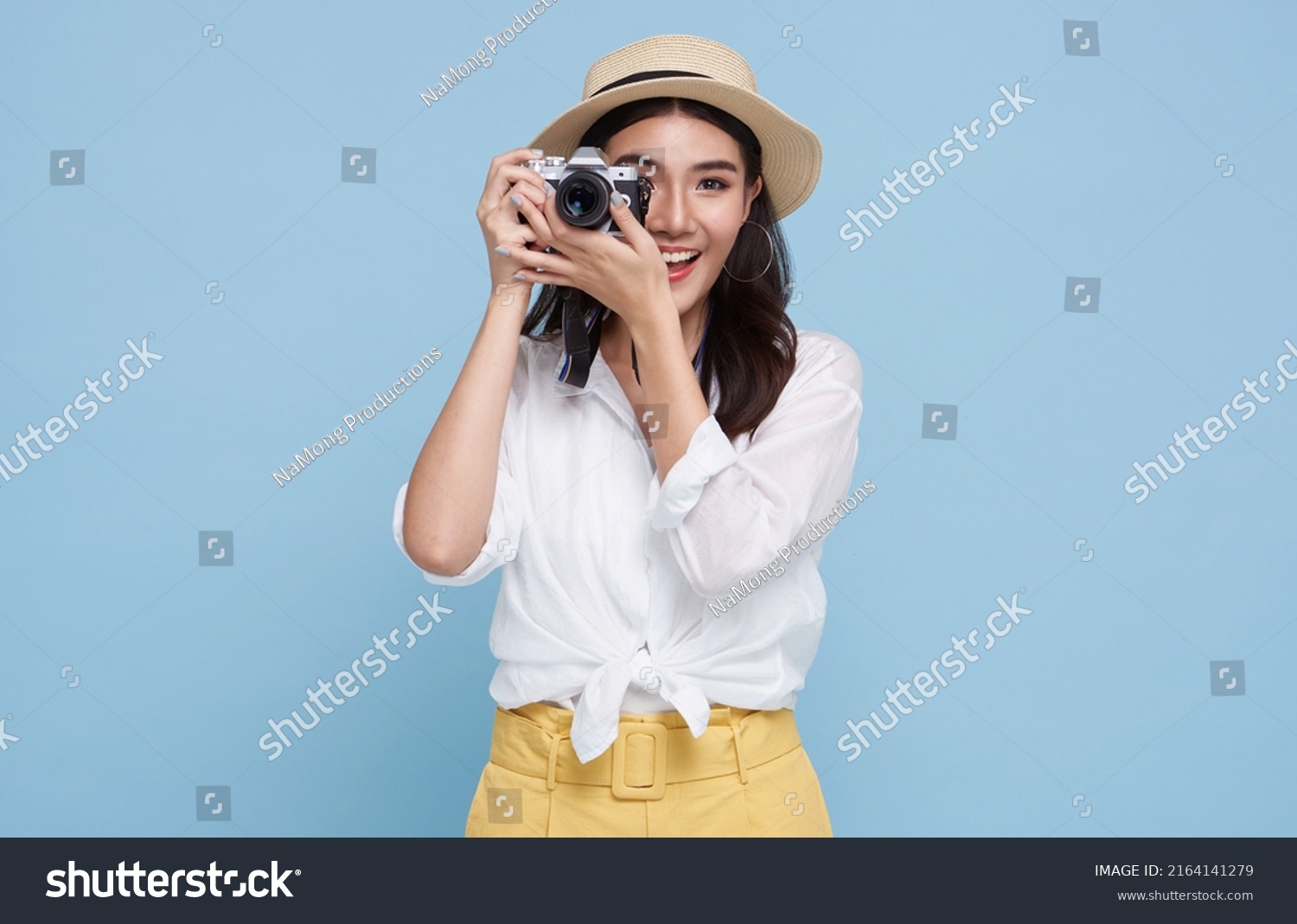smiling Woman photographer is taking images photo with dslr camera isolated studio blue background. #2164141279