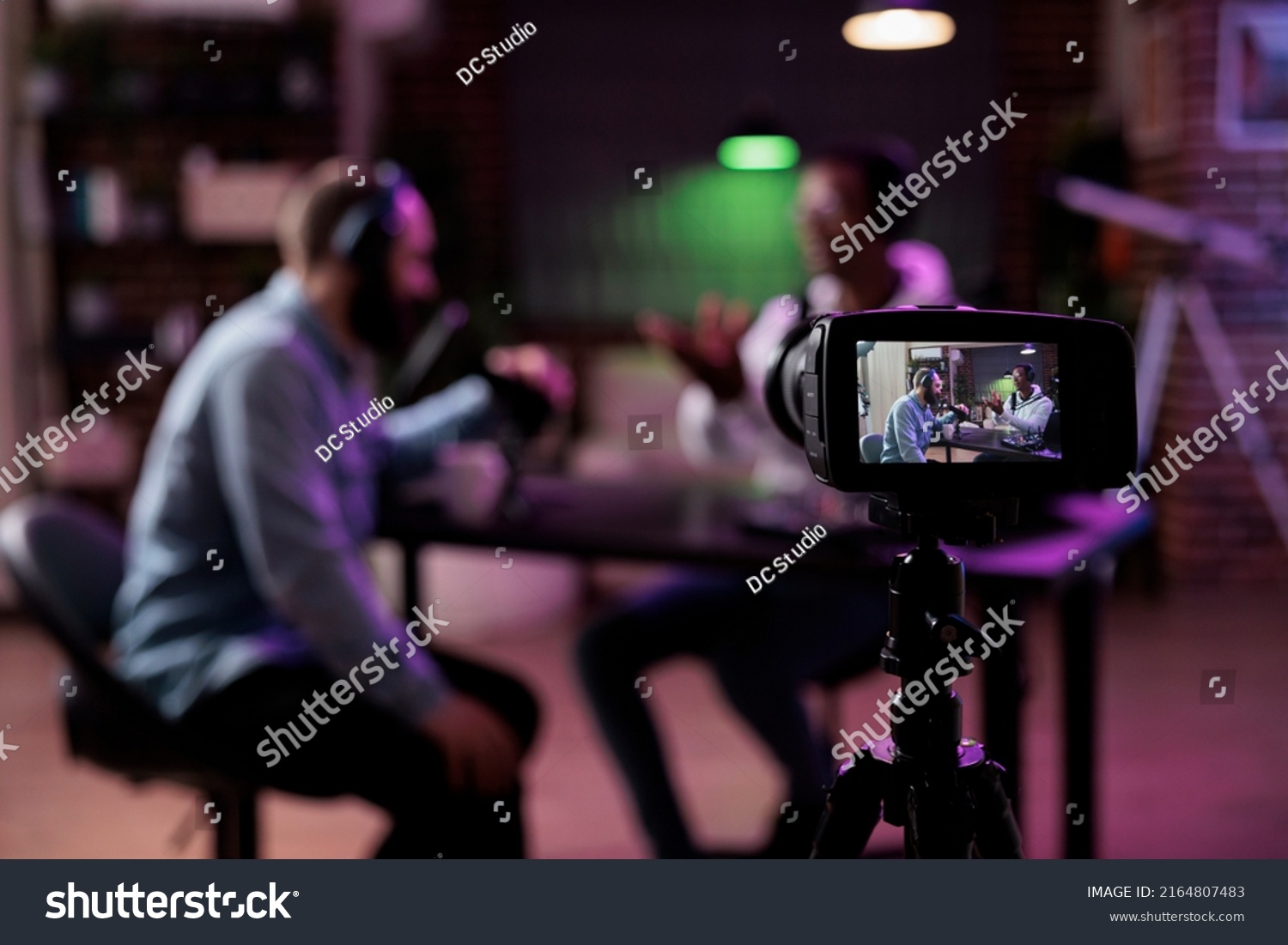 Multiethnic team of people meeting to broadcast internet podcast, recording video discussion on camera. Influencer and guest talking on online livestream to create social media channel content. #2164807483