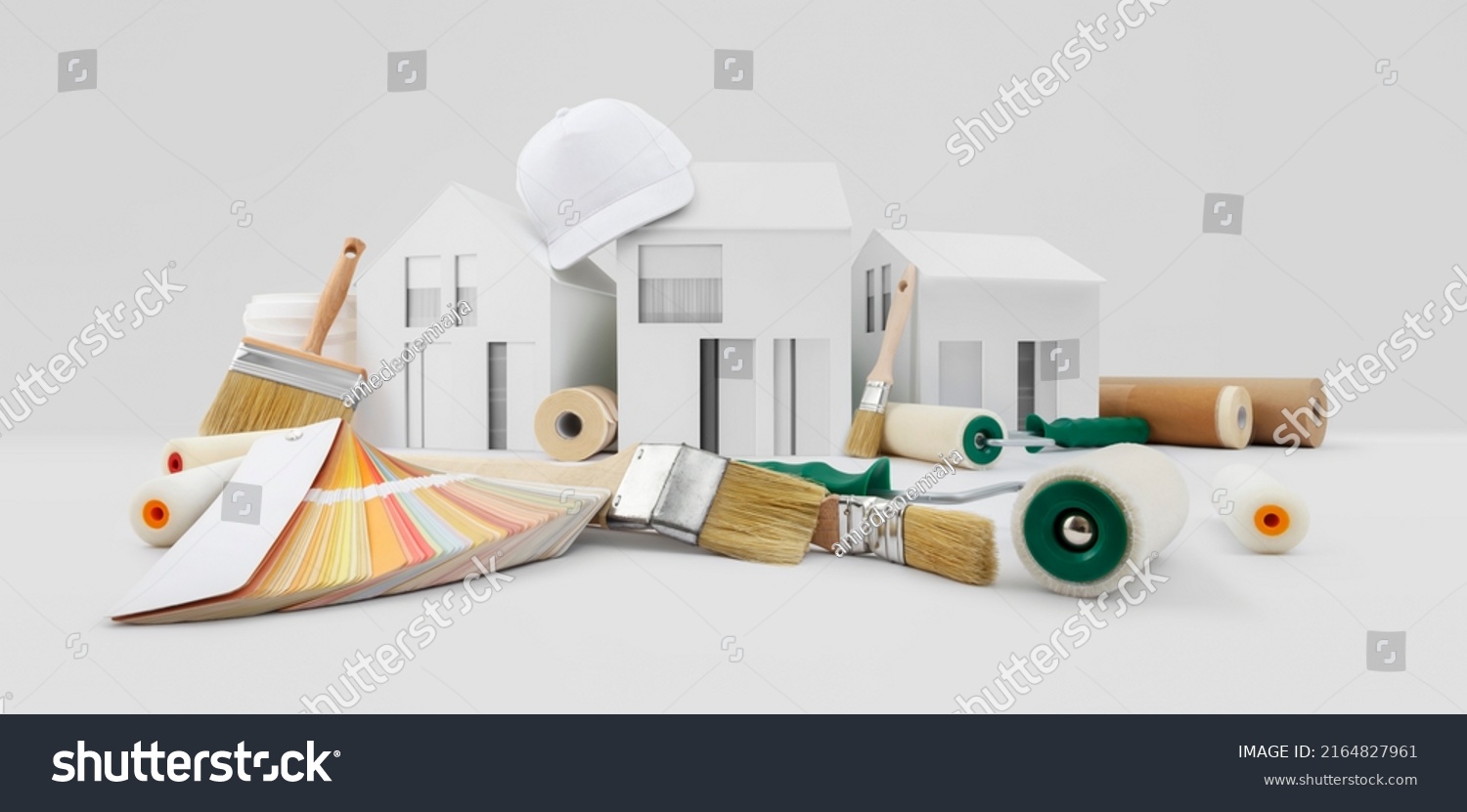 house painter tools, brushes, paint rollers, paper masking tape and colors swatches on desk with model house, supply and service in color shop in the hardware and store of building material. #2164827961