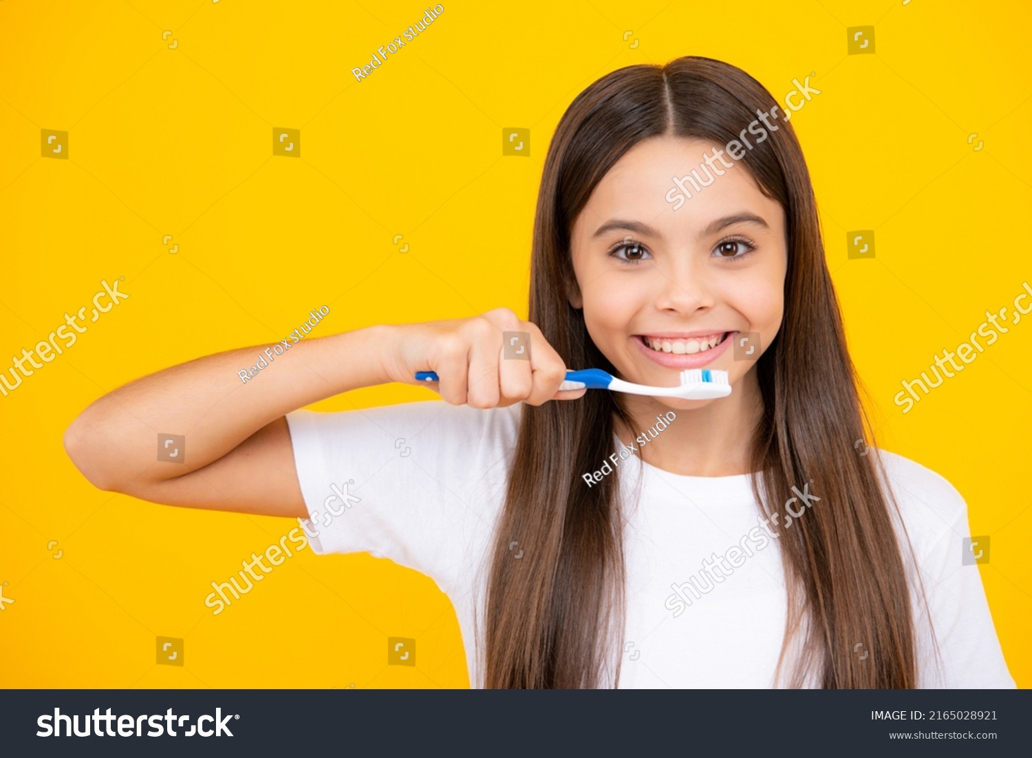 Happy teenager portrait. Teenager girl brushing her teeth over isolated yellow background. Daily hygiene teen child hold toothbrush, morning routine. Dental health oral care. Smiling girl. #2165028921