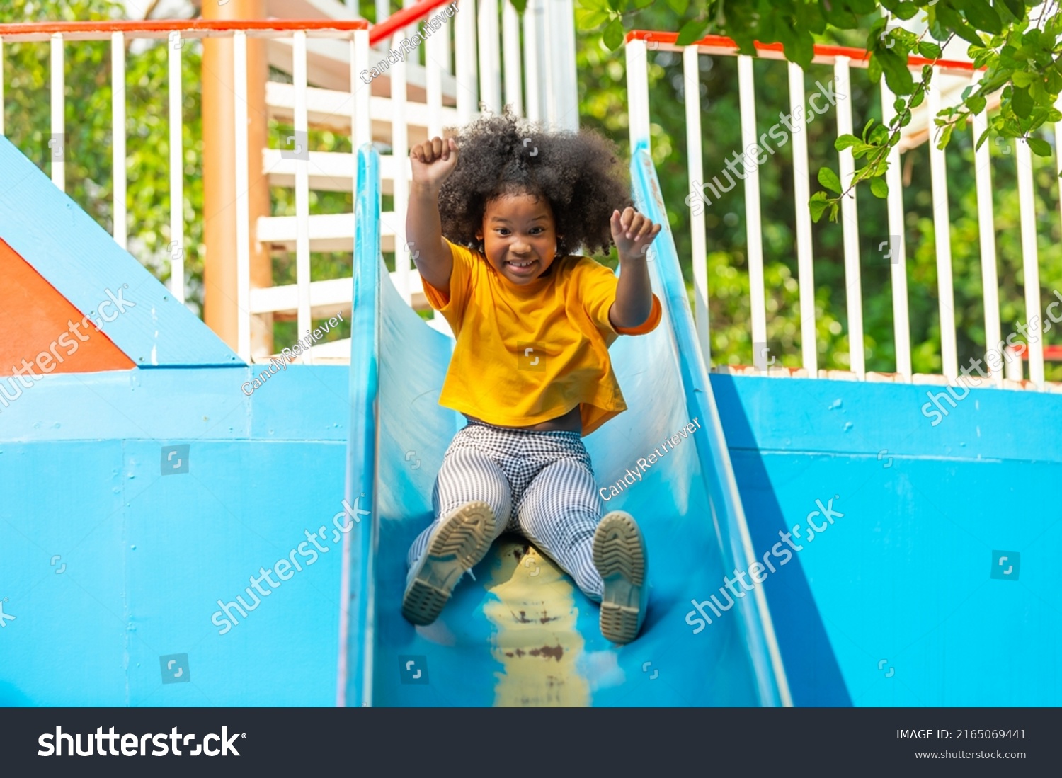 Happy Little African child girl sliding and playing at outdoor playground in the park on summer vacation. Kindergarten children kid enjoy and fun outdoor activity learning and exercising at school. #2165069441