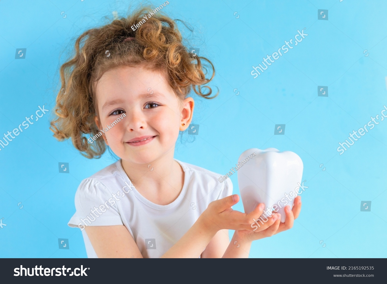Little cute smiling girl holding tooth dent in hand. Kid training oral hygiene. creative medical dentistry . Child learning brushing, cleaning teeth. Prevention of caries in children. dental care kids #2165192535