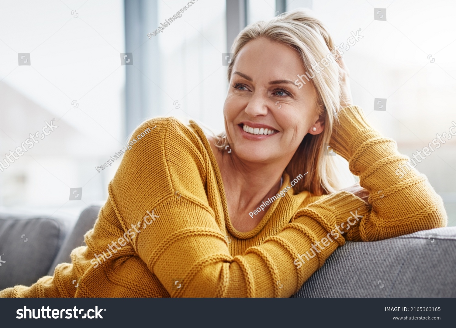 Relaxing really lifts the spirits. Shot of an attractive mature woman relaxing on the sofa at home. #2165363165