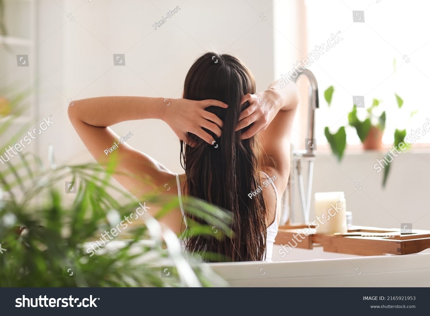 Young woman applying coconut oil onto her hair in bathroom #2165921953
