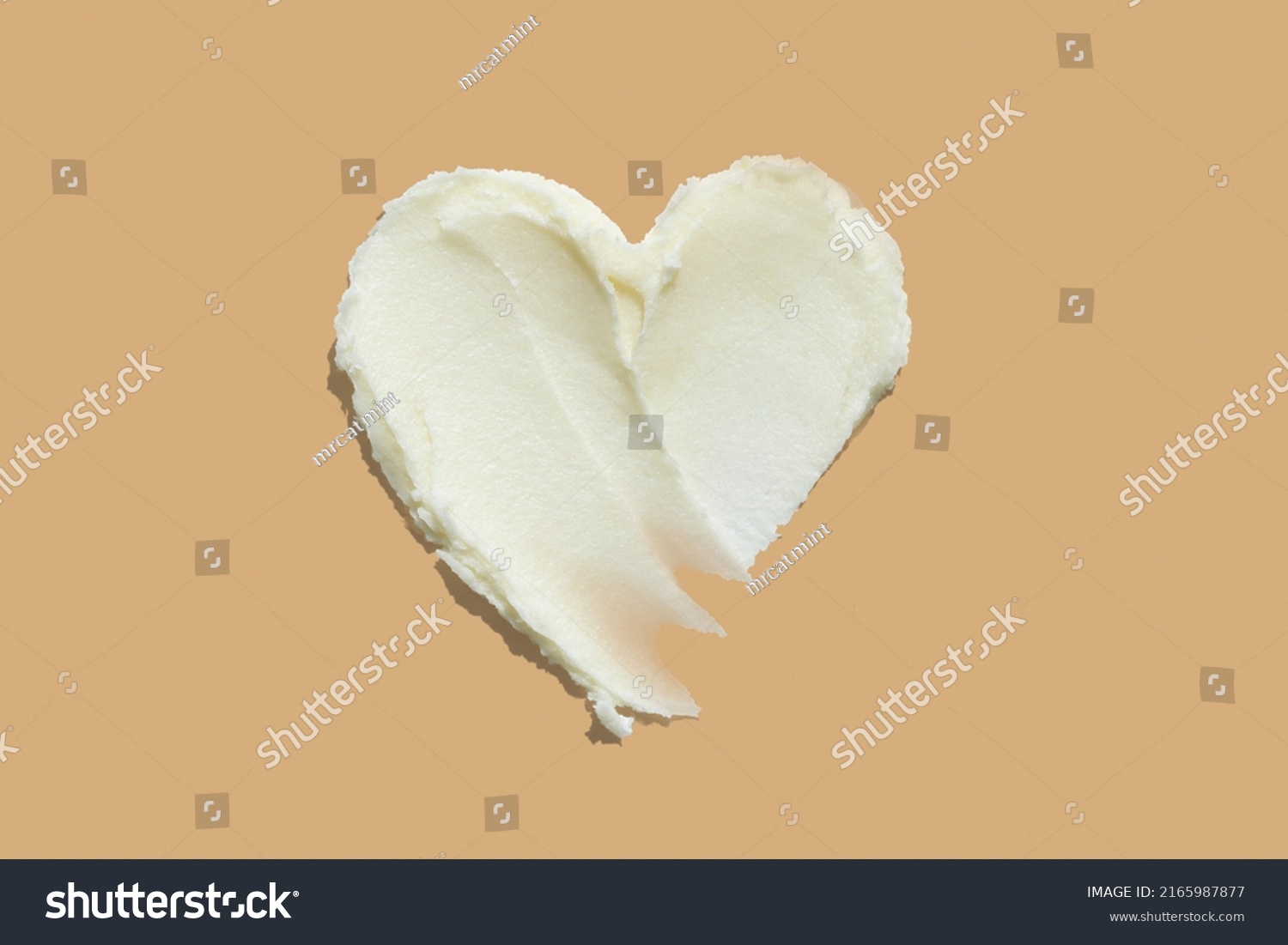 Shea butter cream textured heart shape smear on beige brown colour background, hair and skin care love swatch #2165987877