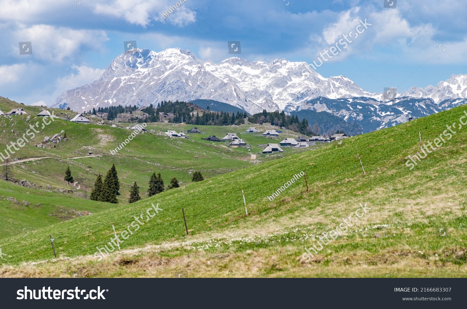 A picture of the landscape of Velika Planina, or Big Pasture Plateau, and its herder huts, with the Kamnik–Savinja Alps on the background. #2166683307