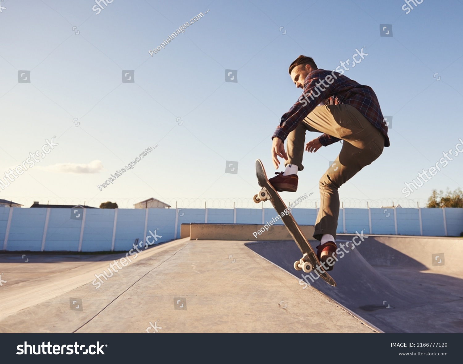 A rad day at the skate park. A young man doing tricks on his skateboard at the skate park. #2166777129