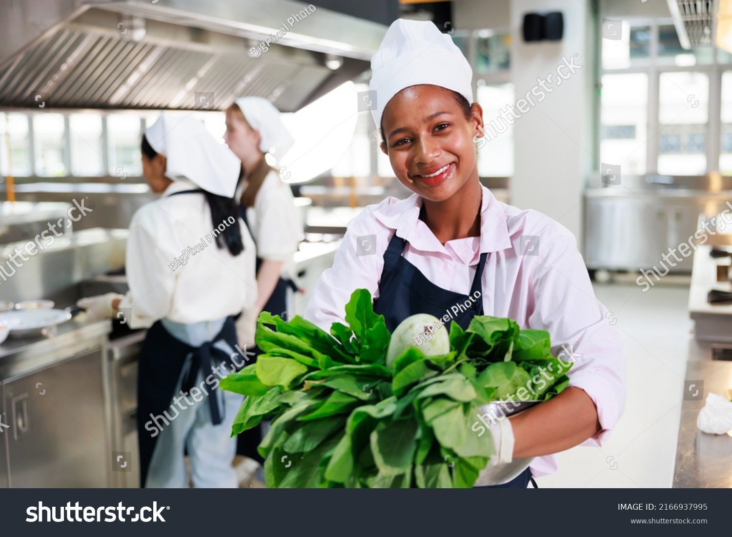 portrait young teen girl cook student. Cooking class. culinary classroom. happy young african woman students holding fresh vegetables for cooking in cooking school.  #2166937995