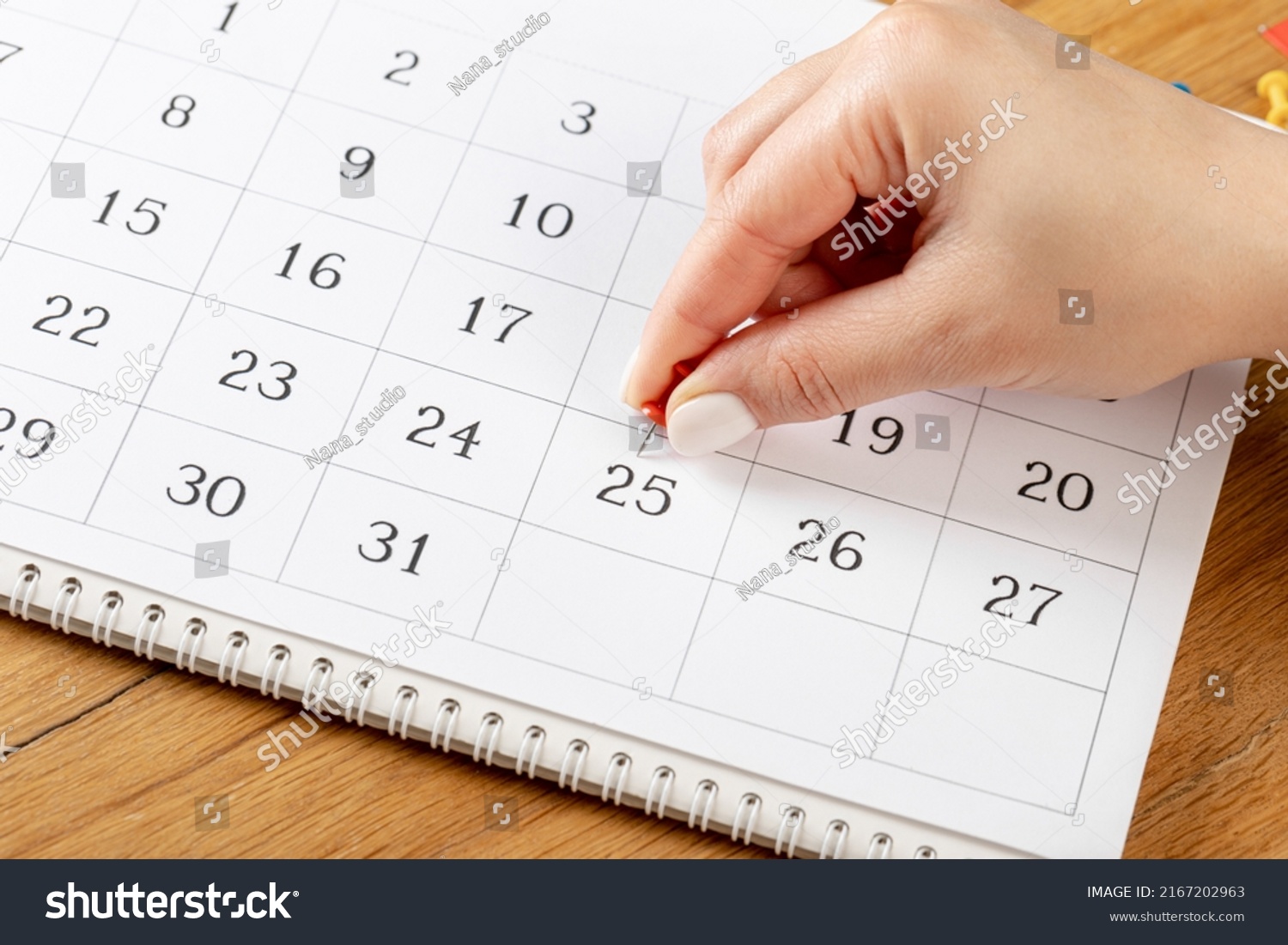 red Hand pin stuck on the day of the month in the calendar, business concept. beautiful female hand fingers #2167202963