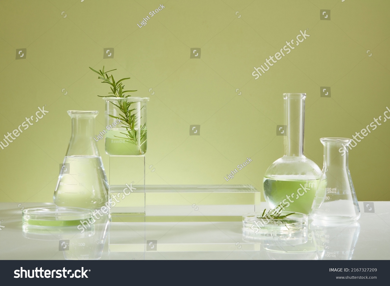 Photoshoot over the course of experiment on green leaf , the research on chemistry lab , fluid in beaker and laboratory equipment and transparent podium with blank space for product #2167327209