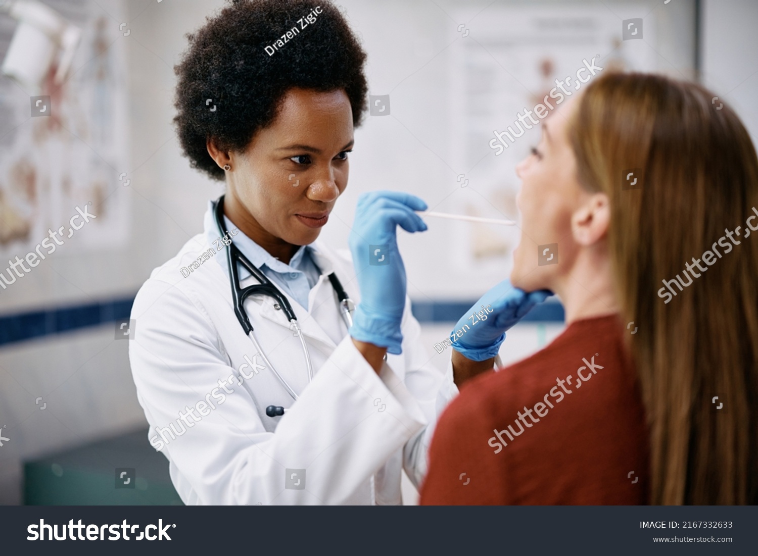 African American doctor examining woman throat during medical appointment at doctor's office. #2167332633