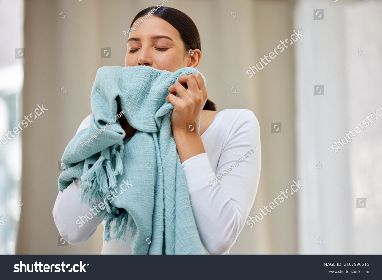 This smell should be bottled. Shot of a young woman smelling freshly cleaned laundry. #2167990515