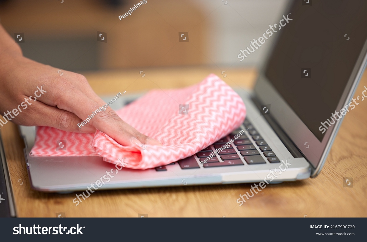 Getting in the crevices. Shot of a woman cleaning the dust from the laptop keyboard. #2167990729