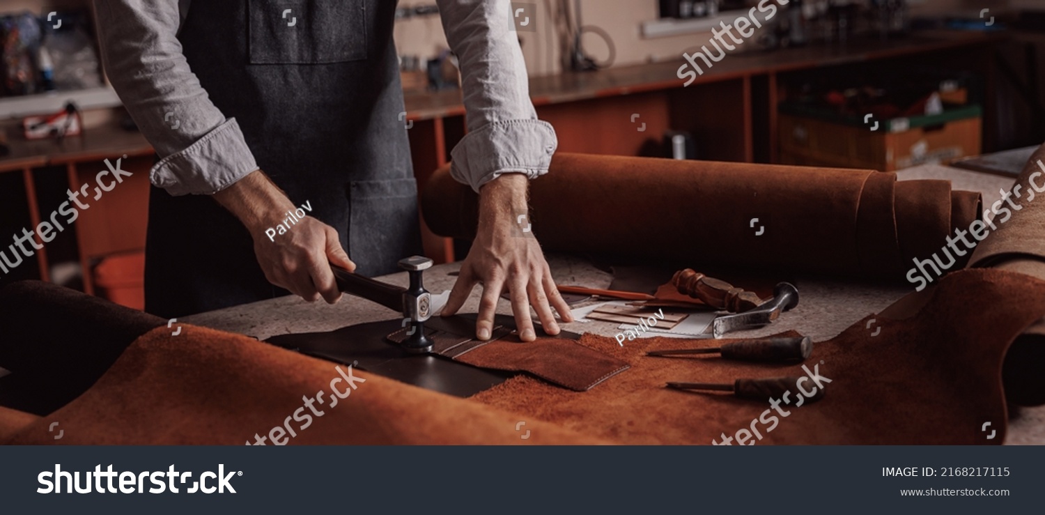 Tailor processing hammers seam on leather goods, banner Handmade craftsman. #2168217115