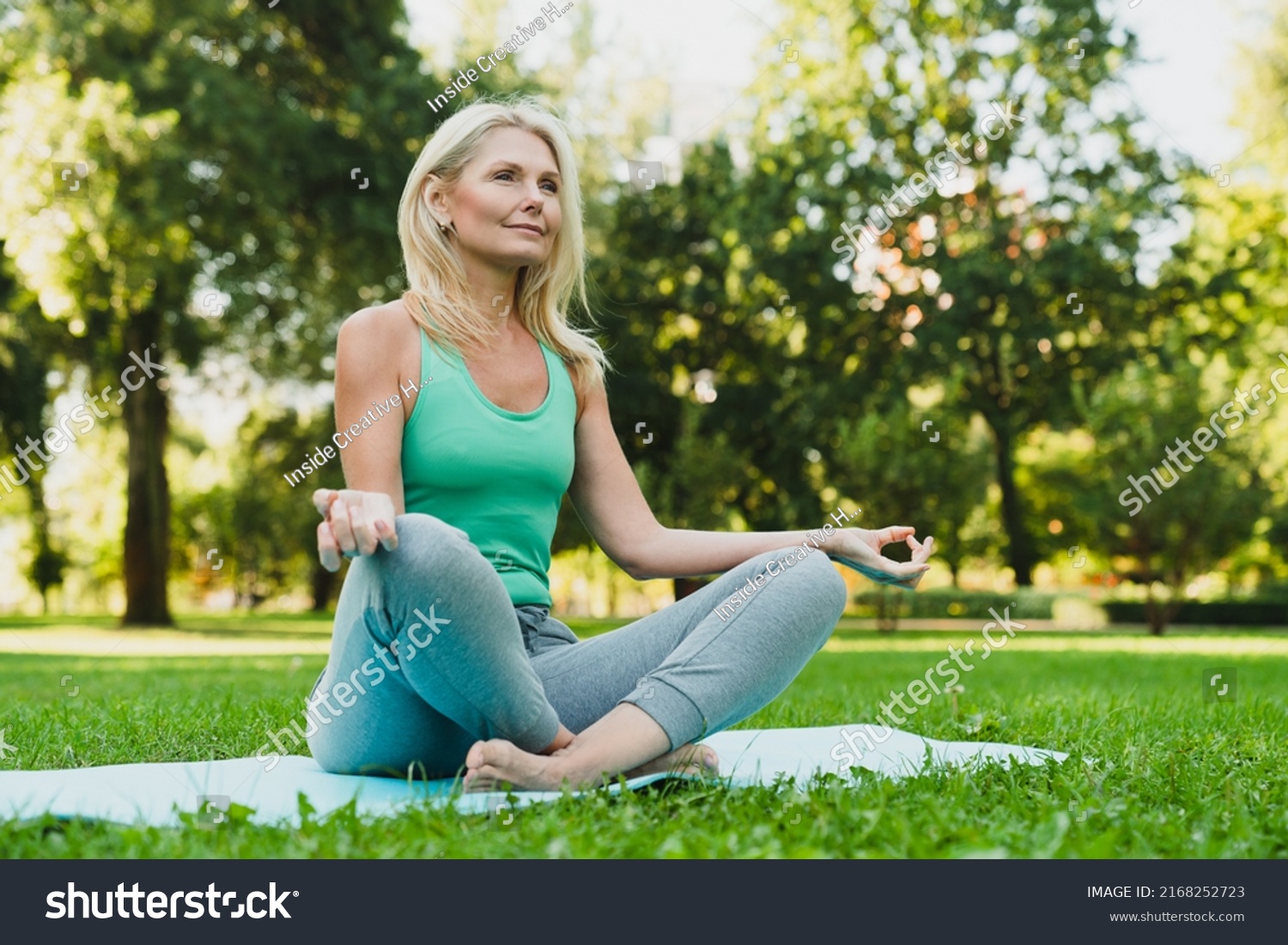 Close up portrait of caucasian mature woman in sporty outfit relaxing meditating feeling zen-like on fitness mat in public park outdoors. Healthy active lifestyle #2168252723