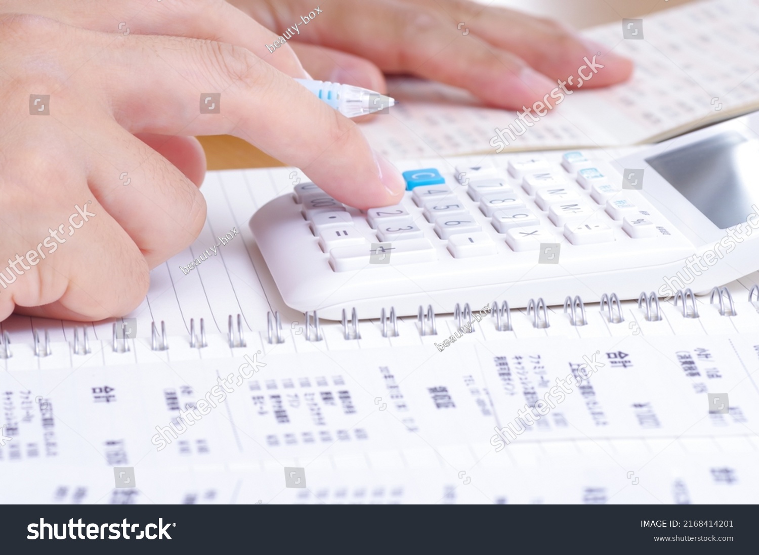 A person who calculates with a calculator while looking at shopping receipts and passbooks written in Japanese #2168414201