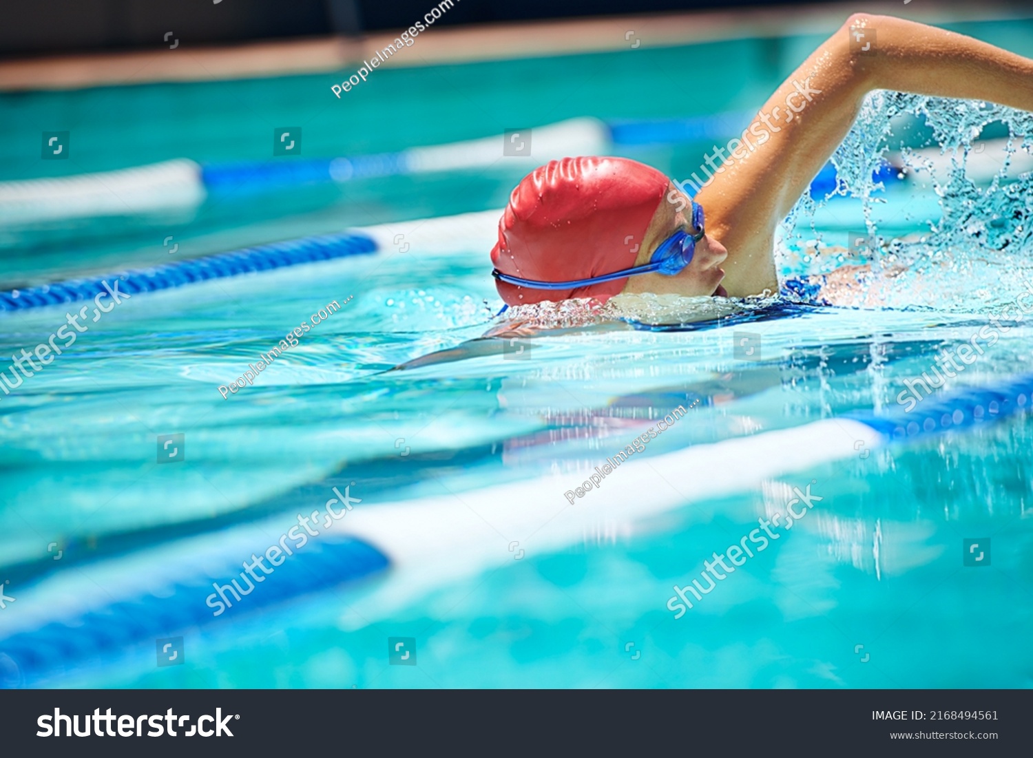 Working on her stroke. Shot of a professional female swimmer freestyle swimming in her lane. #2168494561