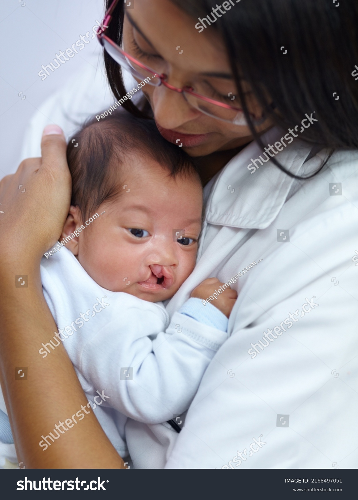 Giving comfort is key in her profession. Shot of a young female nurse holding a baby who has a cleft palate. #2168497051